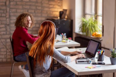Modern bir ofiste çalışan genç iş adamları sohbet ediyorlar.
