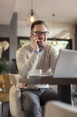 Bir restorandan uzaktan çalışan serbest çalışan bir erkek, telefonda konuşuyor.