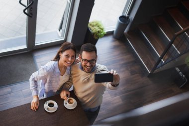 Genç bir çiftin randevularına yüksek açılı bir bakış açısı. Lokanta tezgahının yanında durup selfie çekiyorlar.