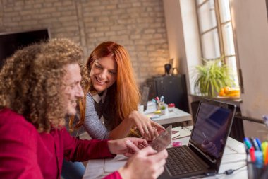 Modern çalışma alanında yeni bir proje üzerinde çalışan grafik tasarımcıları; modern ofiste birlikte çalışan genç iş adamları