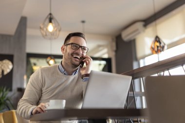 Bir restorandan uzaktan çalışan serbest çalışan bir erkek, telefon görüşmesi yapıyor.