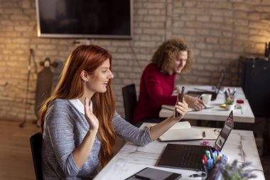 Modern bir ofiste çalışan gençler, ortak çalışma alanında çalışan özgürlükçüler, mola sırasında akıllı telefon kullanan bir kadın.