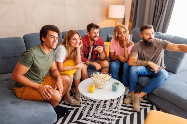 Patlamış mısır yiyen ve TV 'de film izleyen bir grup genç, boş zamanlarını evde birlikte geçiriyorlar.