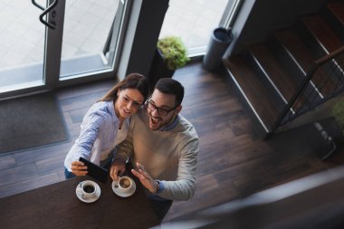 Genç bir çiftin randevularına yüksek açılı bir bakış açısı. Lokanta tezgahının yanında durup selfie çekiyorlar.