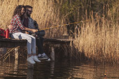 Birbirine aşık çiftler göl rıhtımlarında oturur, balık tutar ve doğada güneşli bir sonbahar gününün tadını çıkarırlar.