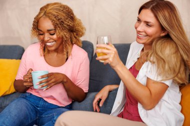İki kadın evde eğleniyor, kahve içiyor ve dedikodu yaparken gülüyorlar.