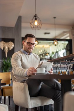 Restoran masasında oturmuş gazete okuyup kahve içen düşünceli bir adamın portresi.
