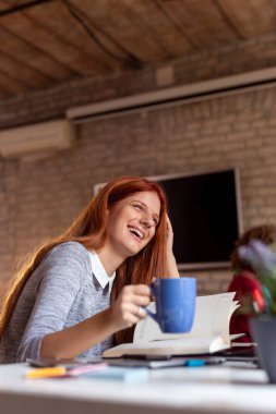Modern bir ofiste çalışan iş adamları, birlikte çalışan serbest çalışanlar, ofis masasında otururken kahve içen kadınlar.