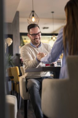 Güzel bir çift restoranda romantik bir öğle yemeği yiyor, masanın karşısında el ele tutuşuyor ve birlikte vakit geçiriyorlar.