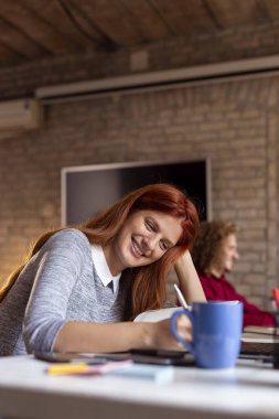 Modern bir ofiste çalışan iş adamları, birlikte çalışan serbest çalışanlar, planlama yapan ve kahve içen kadınlar.