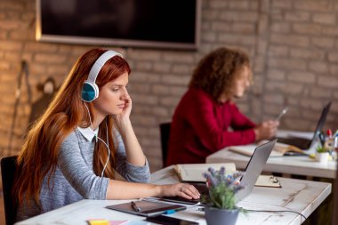 Modern bir ofiste yeni bir proje üzerinde çalışan grafiksel tasarımcı; çalışma alanında çalışan genç iş adamları