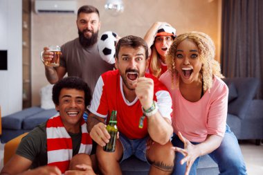 Bir grup neşeli futbol taraftarı, takımlarının evinde TV 'de dünya şampiyonası maçı izlerken attıkları golü kutlayarak ve tezahürat ederek eğleniyorlar.