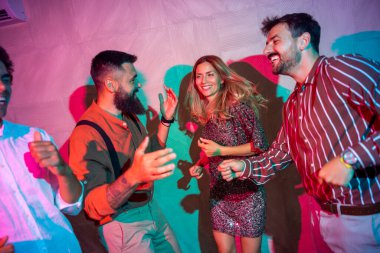 Bir grup neşeli genç arkadaş bir partide şarkı söyleyip dans ediyor.