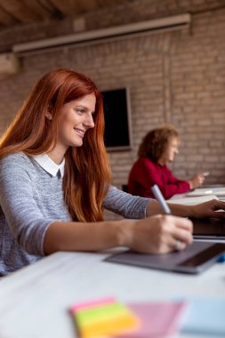 Modern bir ortak çalışma alanında yeni bir proje üzerinde çalışan tasarımcı; çizim tablosunda web tasarımcısı; modern bir ofiste çalışan genç iş adamları