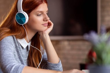 Modern bir çalışma alanında çalışan, kulaklık takan ve dizüstü bilgisayar üzerinde çalışan serbest çalışan bir kadın.