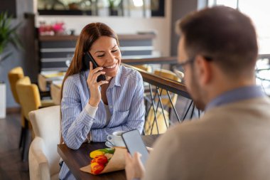 Genç bir kadın restoranda randevudayken telefonla konuşuyor.