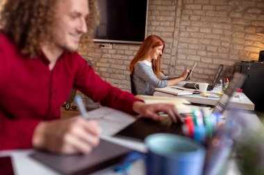 Modern bir ortak çalışma alanında yeni bir proje üzerinde çalışan tasarımcı; çizim tablosunda web tasarımcısı; modern bir ofiste çalışan genç iş adamları