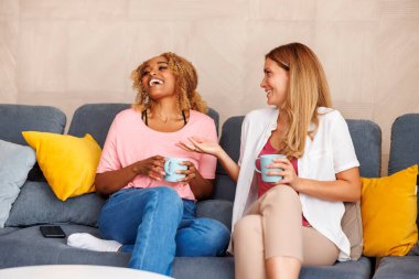 İki kadın evde birlikte vakit geçirip kahve içerek ve fincandan semboller okuyarak fal bakarak eğleniyor.