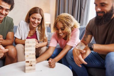 Bir grup neşeli genç arkadaş evde Jenga oynayarak eğleniyor, sırayla kuleden blokları kaldırıyor ve istifliyor, dengeyi sağlamaya çalışıyor ve oyunu kazanmaya çalışıyorlar.