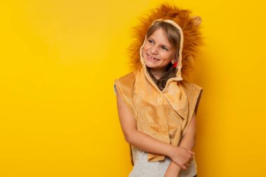 Sarı arka planda izole edilmiş aslan karnavalı kostümü giyen güzel küçük kız.