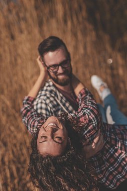 Aşık bir çift dışarıda eğleniyor, erkek kadını kollarında taşıyor, birlikte dönüyor ve gülüyor.