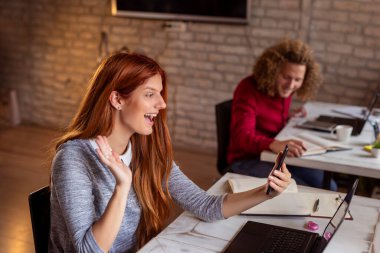 Modern bir ofiste çalışan gençler, ortak çalışma alanında çalışan özgürlükçüler, mola sırasında akıllı telefon kullanan bir kadın.
