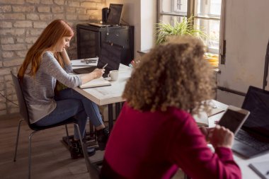 Üniversite okuma odasında okuyan ve sınav için hazırlanan öğrenciler, çevrimiçi dersleri dinlerken notlar alıyorlar.