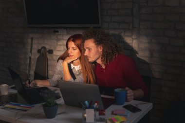 Tasarımcılar bir ofiste yeni bir proje üzerinde birlikte çalışıyorlar; web tasarımcıları bir çizim defterine çizim yapıyorlar