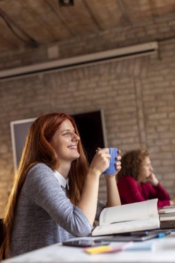 Modern bir ofiste çalışan iş adamları, birlikte çalışan serbest çalışanlar, ofis masasında otururken kahve içen kadınlar.