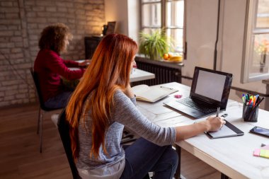 Modern bir ortak çalışma alanında yeni bir proje üzerinde çalışan kadın tasarımcı; çizim tahtası üzerine çizim yapan web tasarımcısı