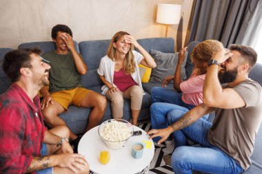 Bir grup neşeli genç arkadaş evde toplanıp kelime tahmin oyunu ve pandomim oynuyorlar.