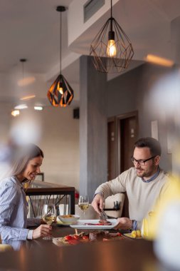 Güzel bir çift restoranda buluşuyor, öğle yemeği yiyor, şarap içiyor ve eğleniyor.