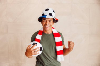 Futbol fanatiği spor forması giyiyor, tezahürat yapıyor takımını kutluyor, gol atıyor ve uluslararası yarışmada maçı kazanıyor.