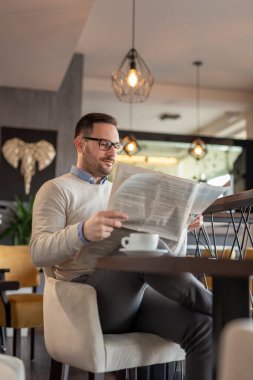 Restoran masasında oturmuş gazete okuyup kahve içen düşünceli bir adamın portresi.