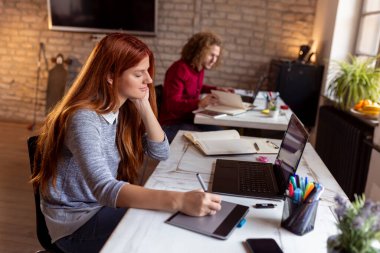 Modern bir ortak çalışma alanında yeni bir proje üzerinde çalışan tasarımcı; çizim tablosunda web tasarımcısı; modern bir ofiste çalışan genç iş adamları
