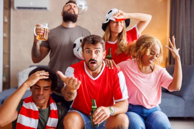 Bir grup futbol taraftarı, takımlarının bir golü kaçırıp maçı kaybetmesi üzerine kızgın ve hayal kırıklığına uğramış bir şekilde TV 'de maç izliyor.