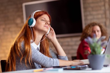 Üniversitenin okuma odasında müzik dinlerken dinlenen, ders çalışmaya ara vermiş güzel bir genç kız öğrenci.