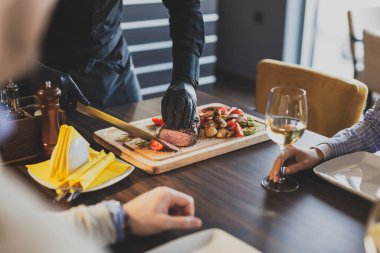 Restoran şefi orta pişmiş biftek dilimliyor ve misafirlere spesiyal servis ediliyor.