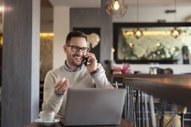 Bir restorandan uzaktan çalışan serbest çalışan bir erkek, telefon görüşmesi yapıyor.