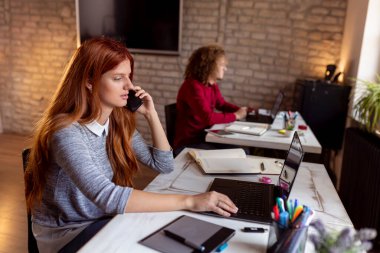 Modern bir ofiste çalışan iş arkadaşları; modern bir iş yerinde çalışan bir kadın telefon görüşmesi yapıyor.