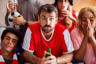 Futbol fanatikleri takımı golü kaçırıp maçı kaybettikten sonra TV 'de dünya şampiyonluğunu izlerken üzülüyorlar.