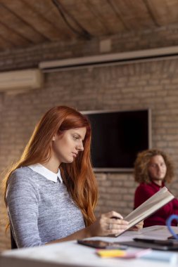 Modern bir ofiste çalışan iş adamları, birlikte çalışan serbest çalışanlar, planlamacıdan notlar okuyan kadınlar.