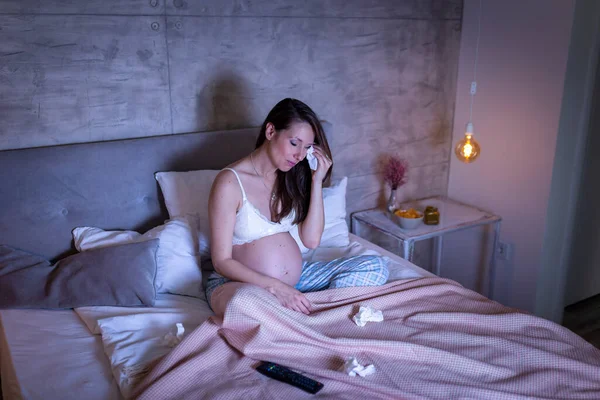 Hamile Bir Kadın Pijamalarıyla Yatakta Oturup Ağlarken Televizyonda Hüzünlü Bir — Stok fotoğraf