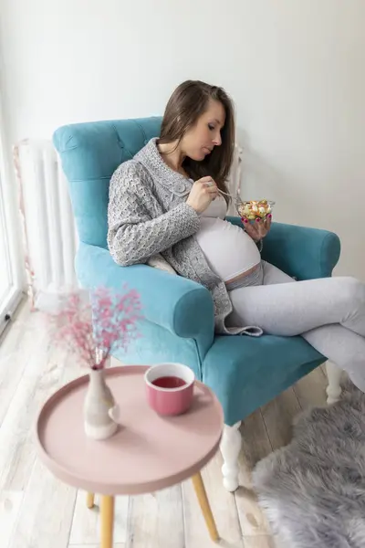 漂亮的孕妇坐在扶手椅上 吃着混合季节蔬菜沙拉 怀孕与健康饮食概念 — 图库照片