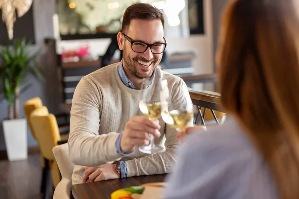 若いカップルはデートに恋し レストランのテーブルに座り ワインをグラスにし 記念日を祝いながら乾杯します — ストック写真