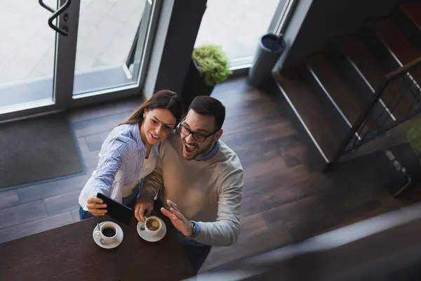 Genç bir çiftin randevularına yüksek açılı bir bakış açısı. Lokanta tezgahının yanında durup selfie çekiyorlar.