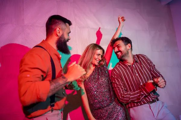 Bir grup neşeli genç bir partide dans edip şarkı söylüyor.