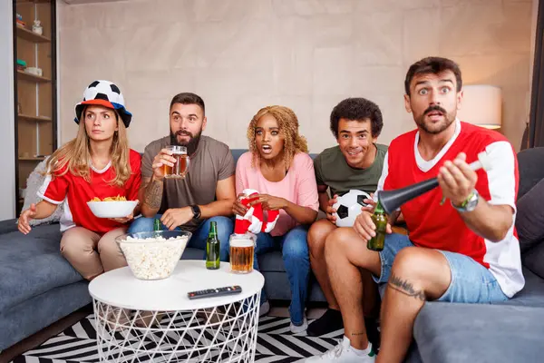 Bir grup neşeli futbol taraftarı evde TV 'de dünya şampiyonası maçı izlerken tezahürat yapıyor.