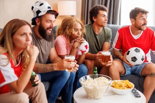 Bir grup arkadaş TV 'de futbol dünya şampiyonası maçı izliyor, tezahürat yapıyor, patlamış mısır yiyor ve bira içiyor.