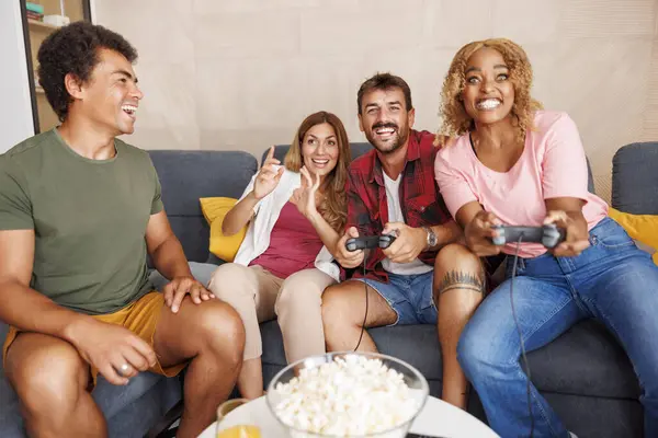 Bir grup neşeli genç arkadaş evde boş zamanlarını geçirirken video oyunları oynayarak eğleniyorlar.